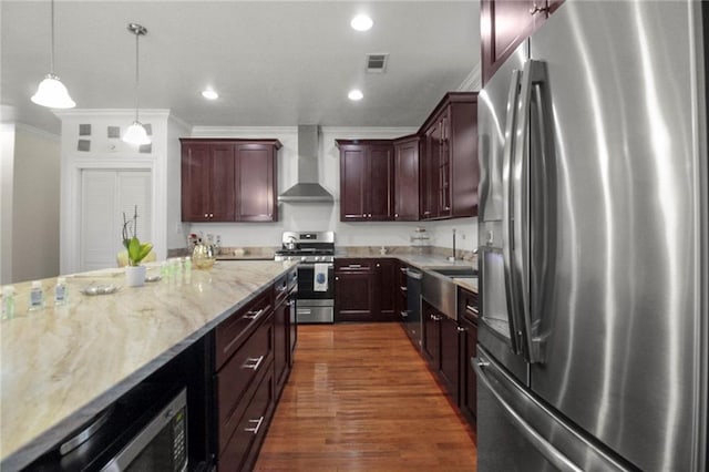 kitchen with ornamental molding, stainless steel appliances, dark wood-type flooring, wall chimney range hood, and hanging light fixtures