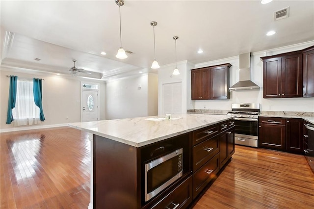 6128 Campus Blvd, New Orleans, LA 70126 - kitchen featuring wall chimney exhaust hood, stainless steel appliances, open floor plan, a center island, and hardwood / wood-style floors