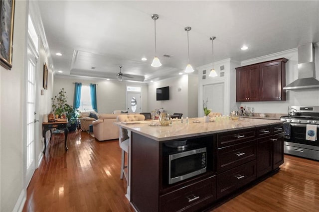 kitchen featuring a breakfast bar, dark wood-type flooring, wall chimney exhaust hood, a kitchen island, and stainless steel appliances