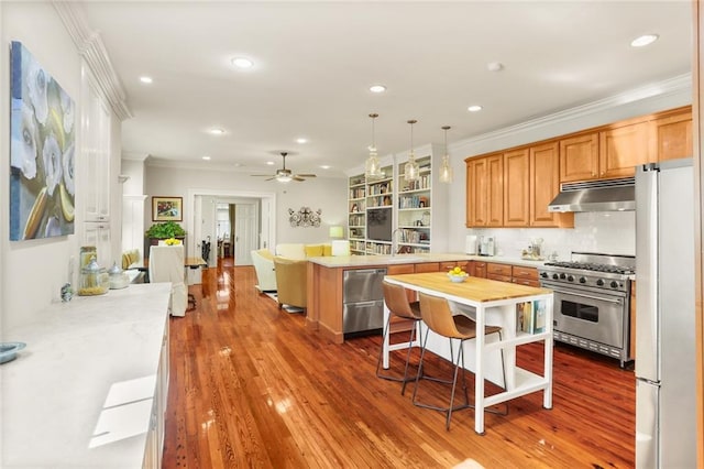 kitchen featuring a kitchen breakfast bar, hanging light fixtures, hardwood / wood-style flooring, appliances with stainless steel finishes, and kitchen peninsula