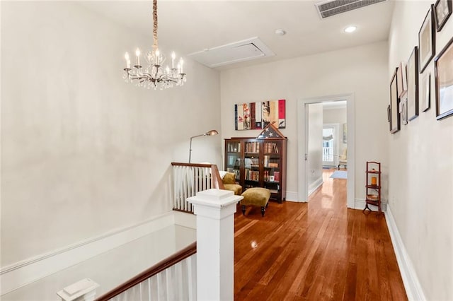 hallway featuring wood-type flooring and an inviting chandelier