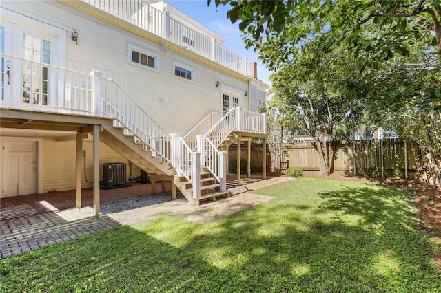 rear view of property with central AC, a patio area, and a lawn