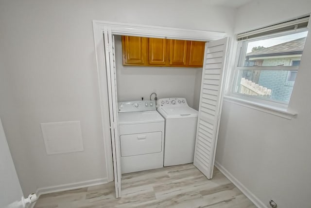 clothes washing area featuring cabinets, separate washer and dryer, and light hardwood / wood-style flooring