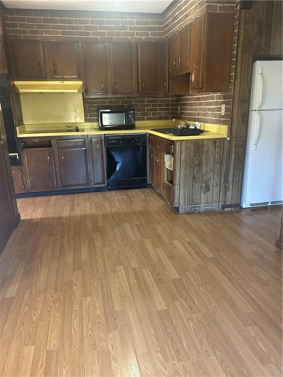 kitchen featuring sink, light hardwood / wood-style flooring, backsplash, dark brown cabinets, and black appliances