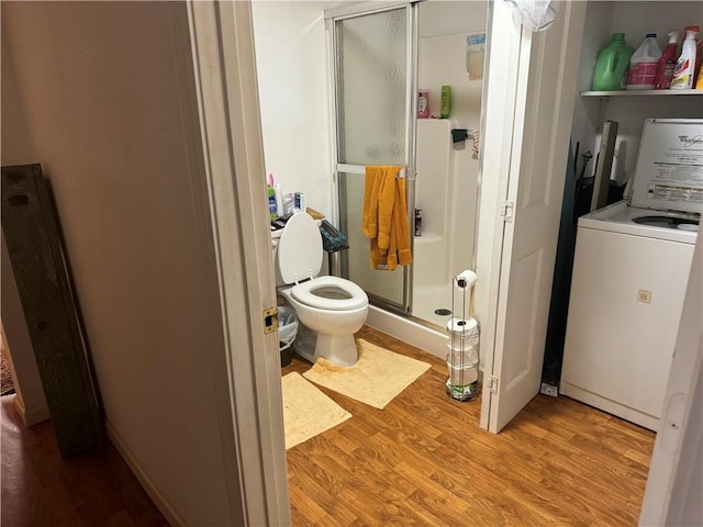 bathroom featuring washer / dryer, hardwood / wood-style flooring, toilet, and a shower with door