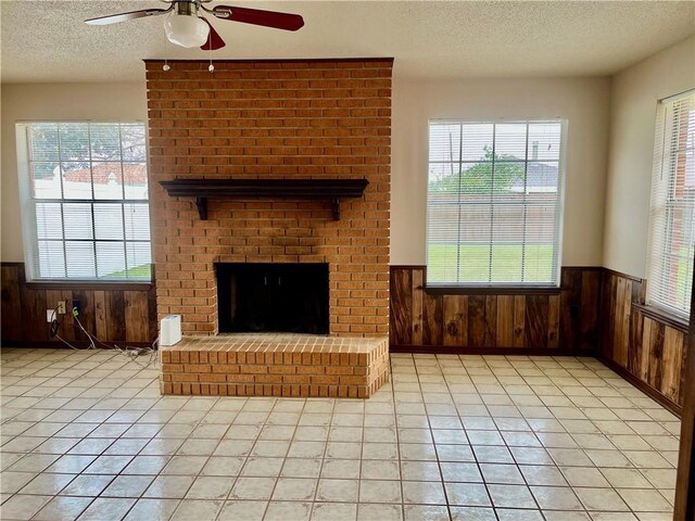 living room featuring a textured ceiling, wooden walls, light wood-type flooring, crown molding, and ceiling fan