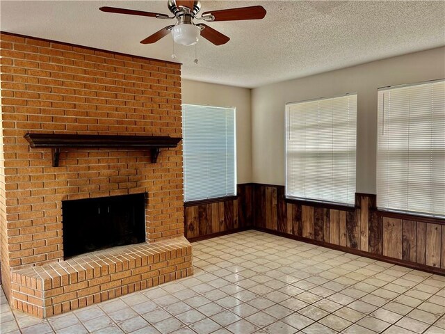 foyer entrance featuring light tile patterned flooring, a textured ceiling, ceiling fan, and a brick fireplace