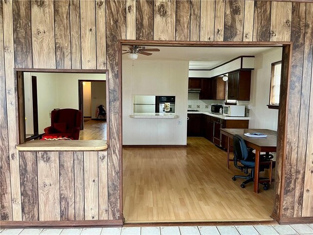 unfurnished living room with a fireplace, a textured ceiling, ceiling fan, and wooden walls