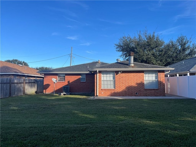 rear view of property with a yard, a fenced backyard, and brick siding