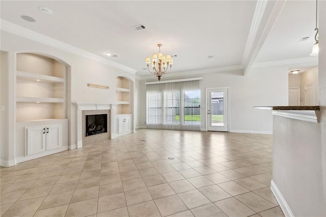 unfurnished living room featuring built in shelves, light tile patterned floors, ornamental molding, and a chandelier