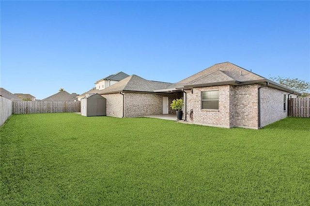 back of property featuring an outbuilding, a fenced backyard, a shed, a lawn, and brick siding