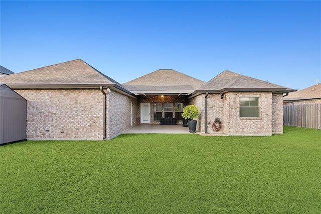 rear view of property with brick siding, fence, a yard, and a patio area