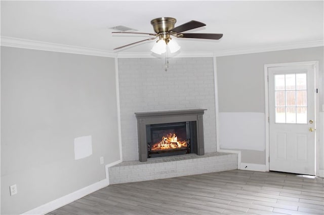 interior details with a fireplace, ceiling fan, crown molding, and wood-type flooring