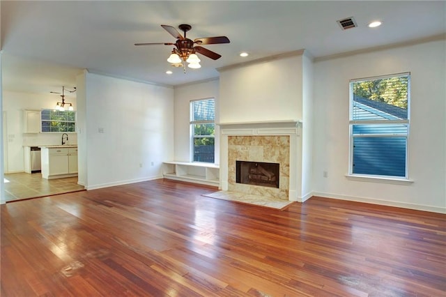 unfurnished living room featuring a tile fireplace, light hardwood / wood-style flooring, and plenty of natural light