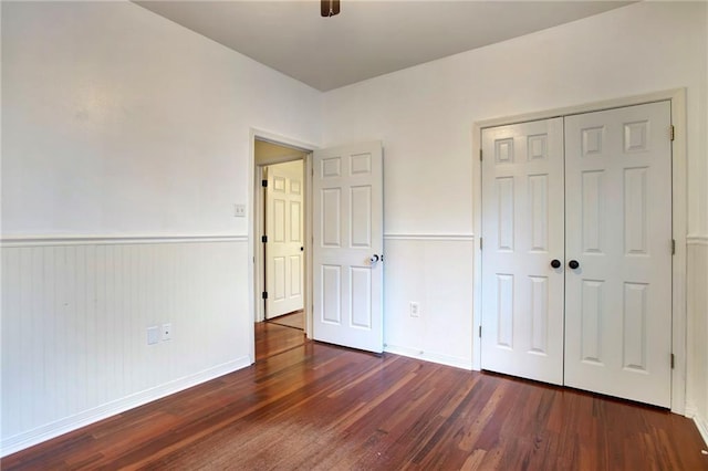 unfurnished bedroom with ceiling fan, a closet, and dark wood-type flooring