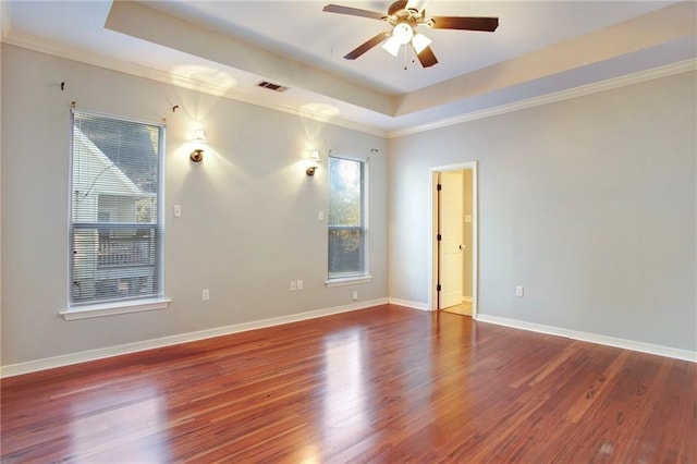 empty room with hardwood / wood-style floors, a tray ceiling, ceiling fan, and ornamental molding