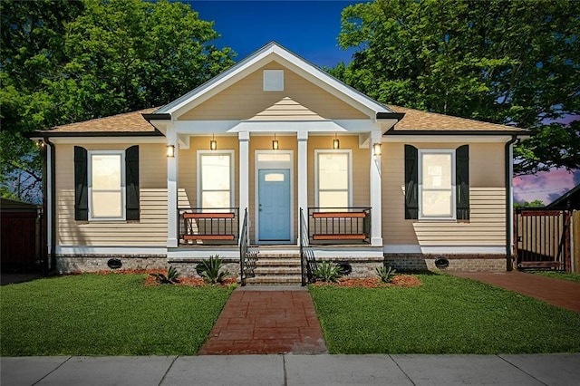 bungalow with a porch, a front yard, and fence