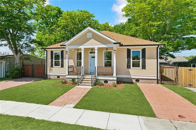 bungalow-style home with a porch, a shingled roof, fence, a gate, and a front lawn