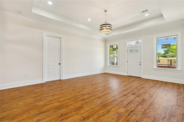 foyer featuring a tray ceiling, hardwood / wood-style flooring, plenty of natural light, and visible vents