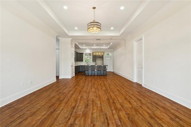 unfurnished living room with dark wood-style floors, a tray ceiling, decorative columns, recessed lighting, and baseboards