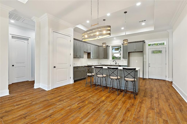 kitchen featuring dark wood-style floors, ornamental molding, gray cabinets, and a center island