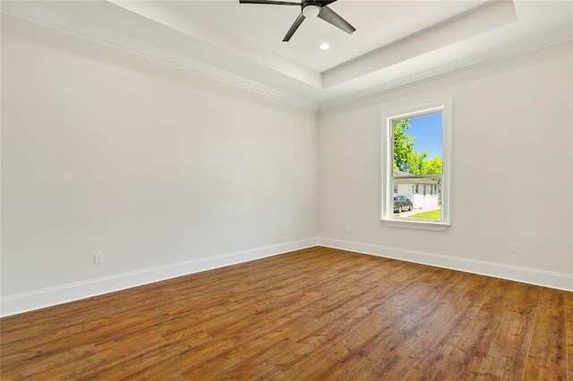 spare room with a tray ceiling, recessed lighting, baseboards, ceiling fan, and hardwood / wood-style floors