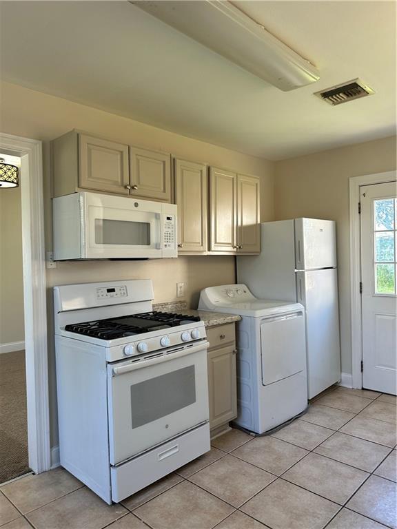 kitchen with washer / clothes dryer, light tile patterned floors, and white appliances