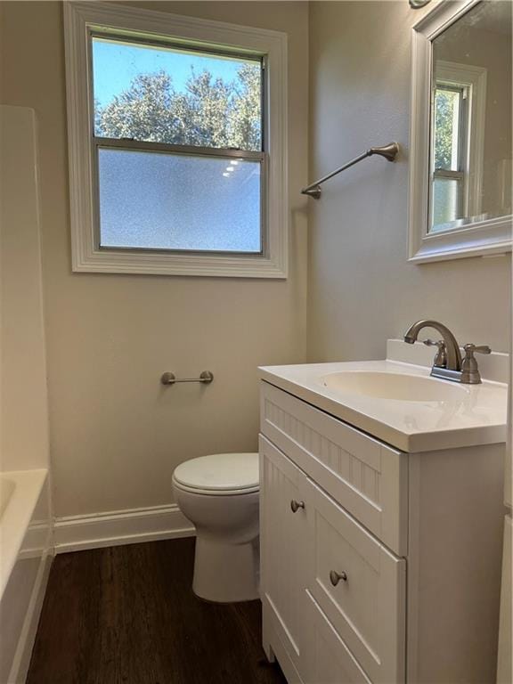 bathroom featuring plenty of natural light, vanity, hardwood / wood-style floors, and toilet