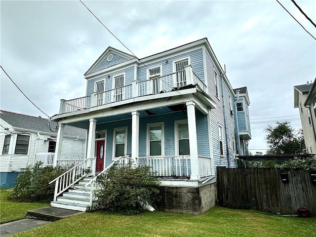 view of front of house with a porch, a balcony, and a front lawn