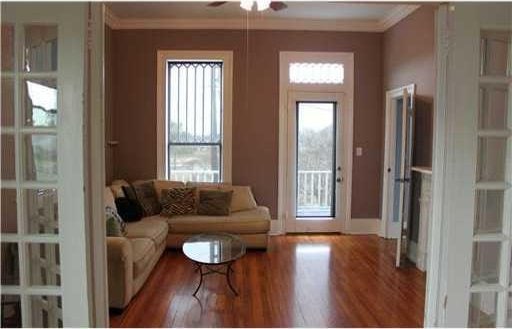 living room with hardwood / wood-style flooring, ceiling fan, and ornamental molding