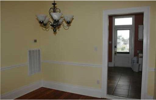 unfurnished dining area featuring a chandelier and wood-type flooring