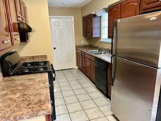 kitchen featuring black appliances, light tile patterned floors, and sink