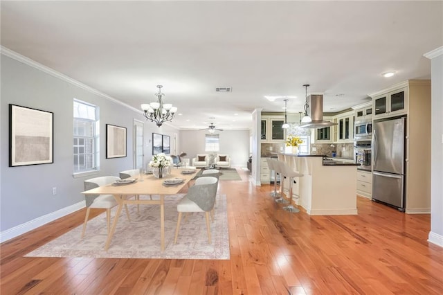 dining room featuring ceiling fan with notable chandelier, light hardwood / wood-style flooring, and ornamental molding