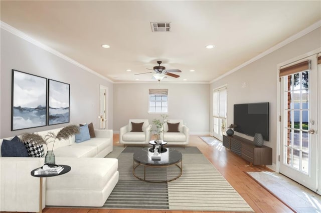 living room featuring ceiling fan, crown molding, and light hardwood / wood-style flooring