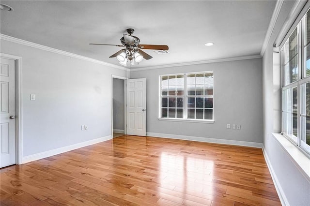 empty room featuring a wealth of natural light, light hardwood / wood-style flooring, and crown molding