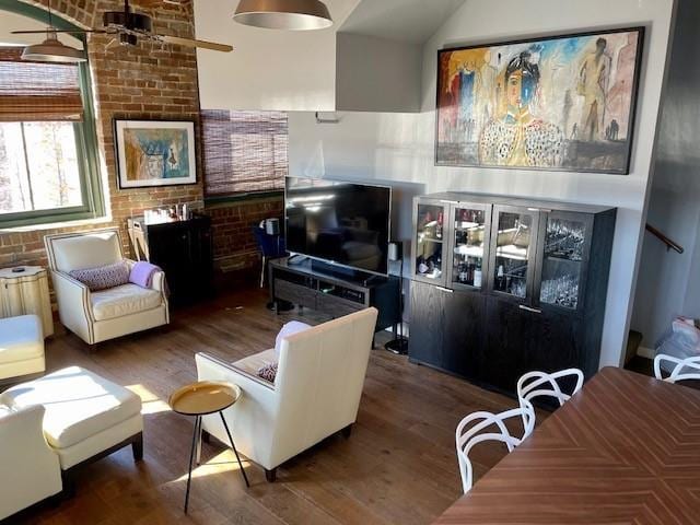 living room with vaulted ceiling, ceiling fan, brick wall, and dark hardwood / wood-style floors