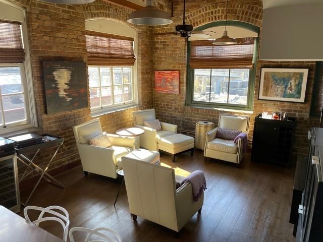 living area featuring ceiling fan, brick wall, dark hardwood / wood-style flooring, and a wealth of natural light