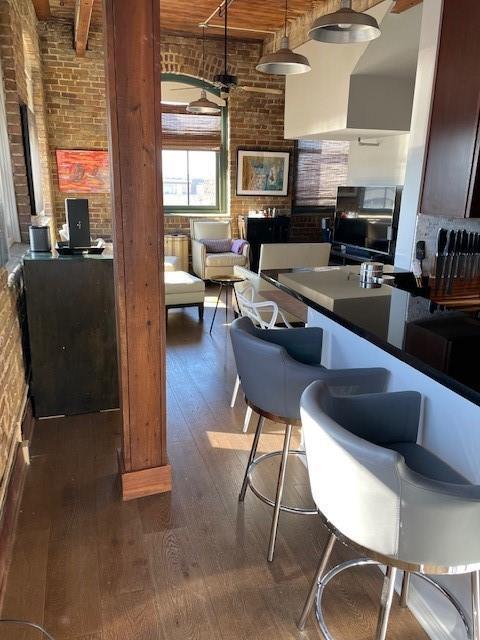 kitchen with hardwood / wood-style floors, ceiling fan, a towering ceiling, and brick wall