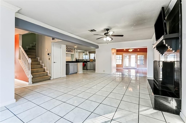 unfurnished living room with ceiling fan, light tile patterned floors, ornamental molding, and french doors