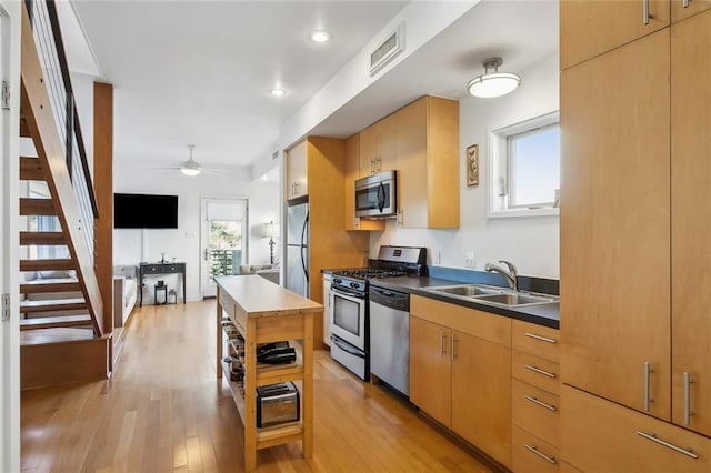 kitchen featuring light brown cabinets, sink, light hardwood / wood-style flooring, ceiling fan, and stainless steel appliances