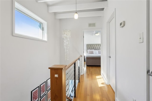 corridor featuring beam ceiling and light hardwood / wood-style floors