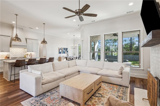 living room featuring ceiling fan with notable chandelier, dark hardwood / wood-style floors, and ornamental molding