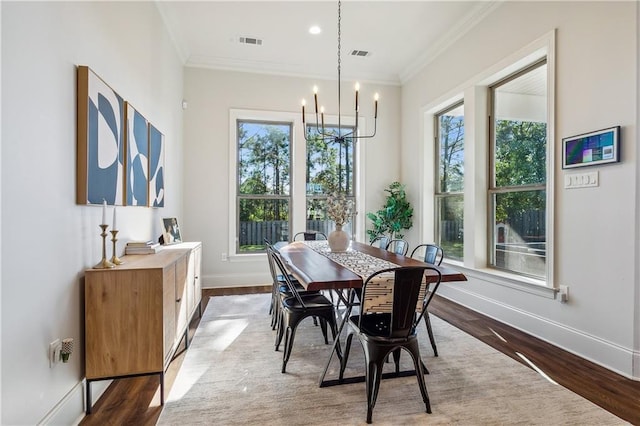 dining room with wood-type flooring, crown molding, and a notable chandelier