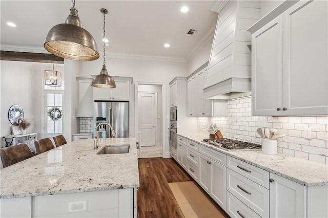 kitchen featuring a kitchen island with sink, stainless steel appliances, and hanging light fixtures