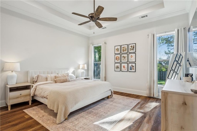 bedroom featuring ceiling fan, dark hardwood / wood-style floors, crown molding, and a tray ceiling