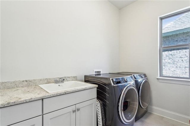 laundry area featuring washer and dryer, sink, light tile patterned floors, and cabinets