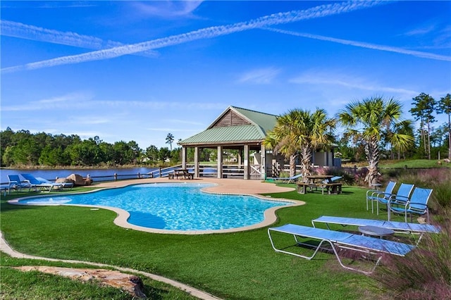 view of swimming pool with a lawn, a patio area, and a water view