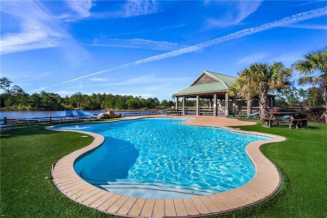 view of swimming pool featuring a water view and a lawn