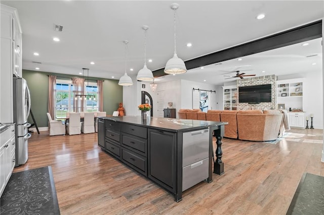 kitchen with hanging light fixtures, stainless steel refrigerator, a center island, and white cabinets