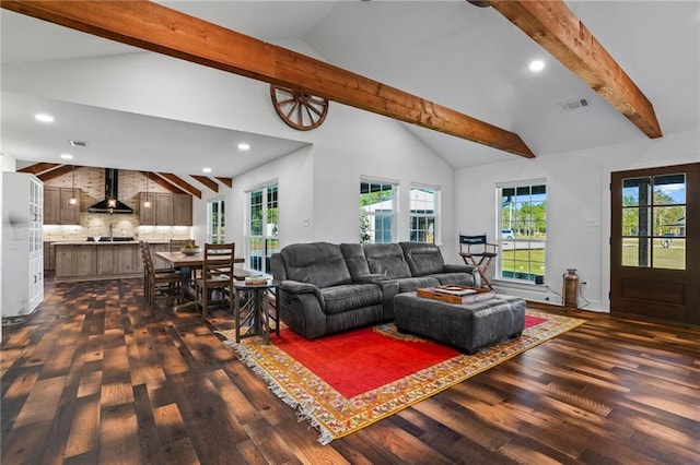 living room with a wealth of natural light, dark hardwood / wood-style floors, and beamed ceiling